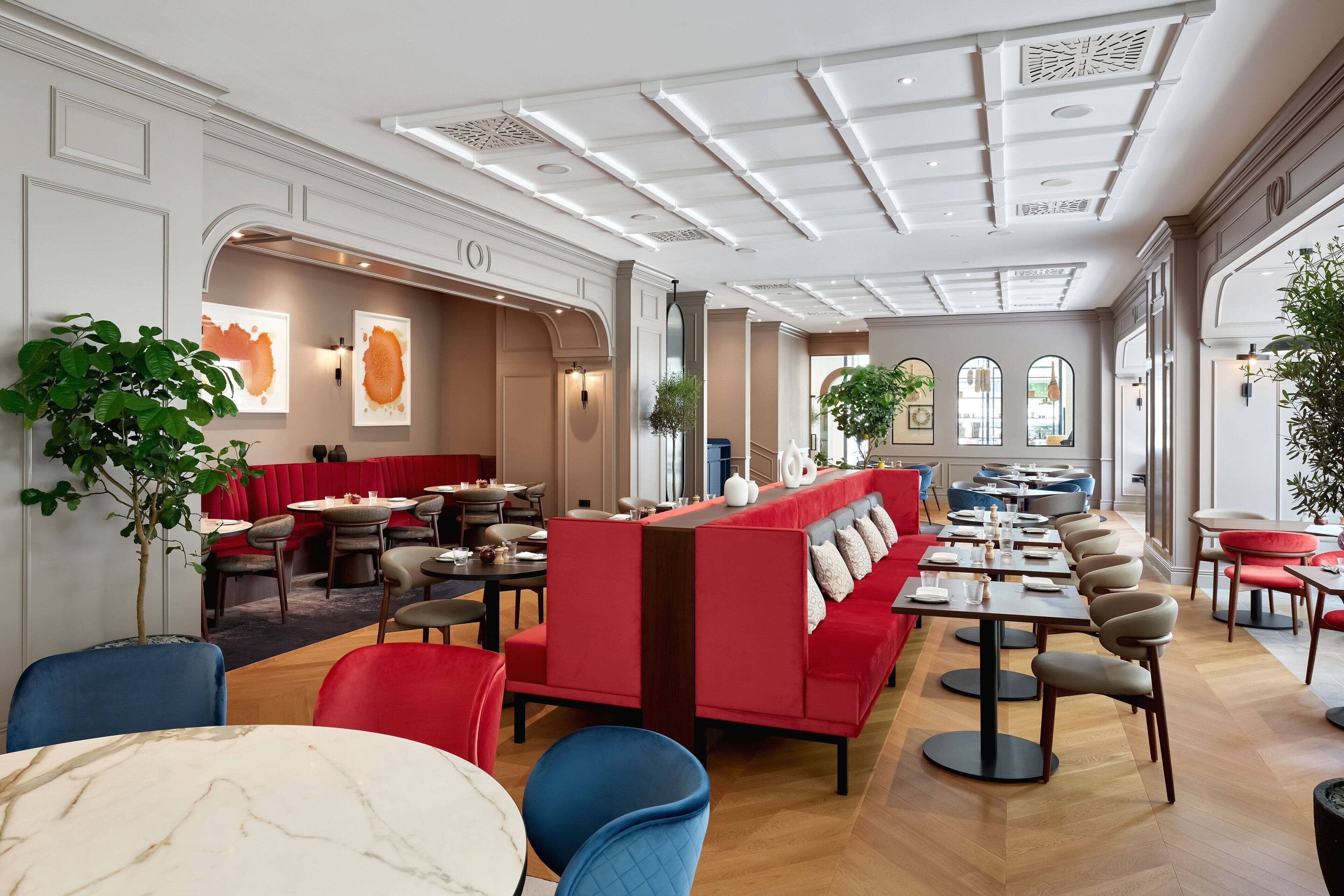 A spacious restaurant with high ceilings, red seating areas, and modern decor.