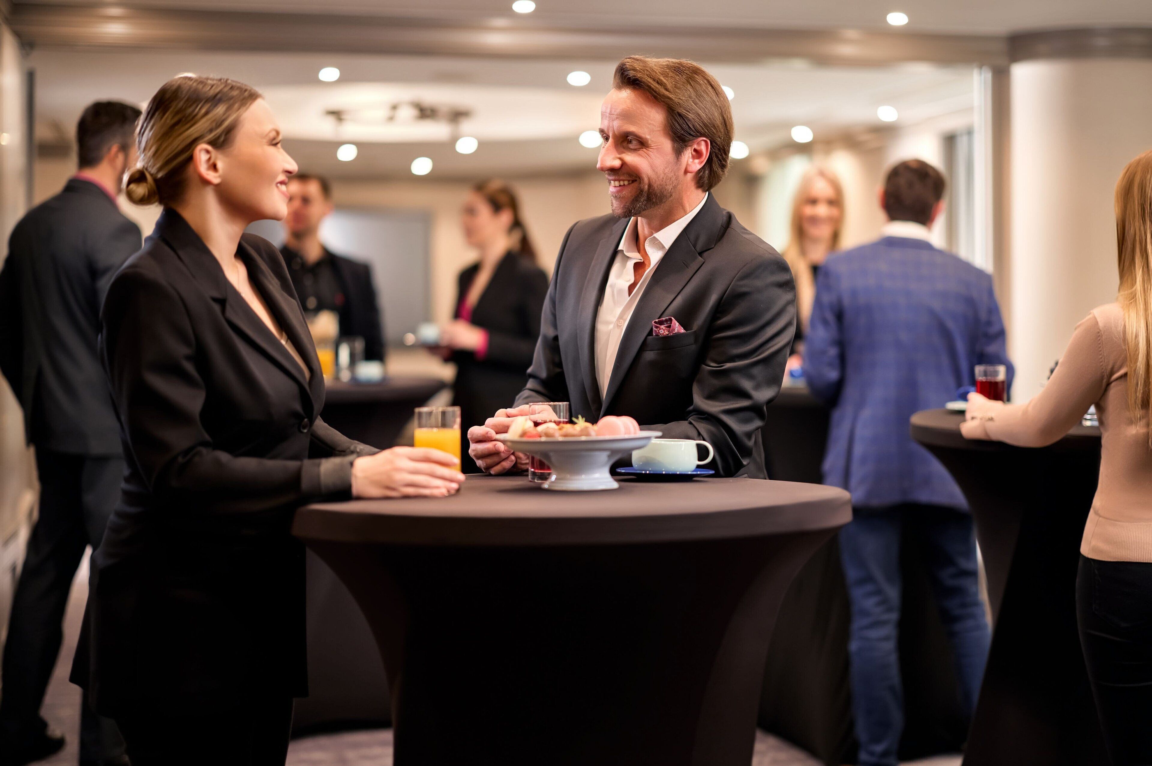 A networking event with round tables and attendees in business attire.