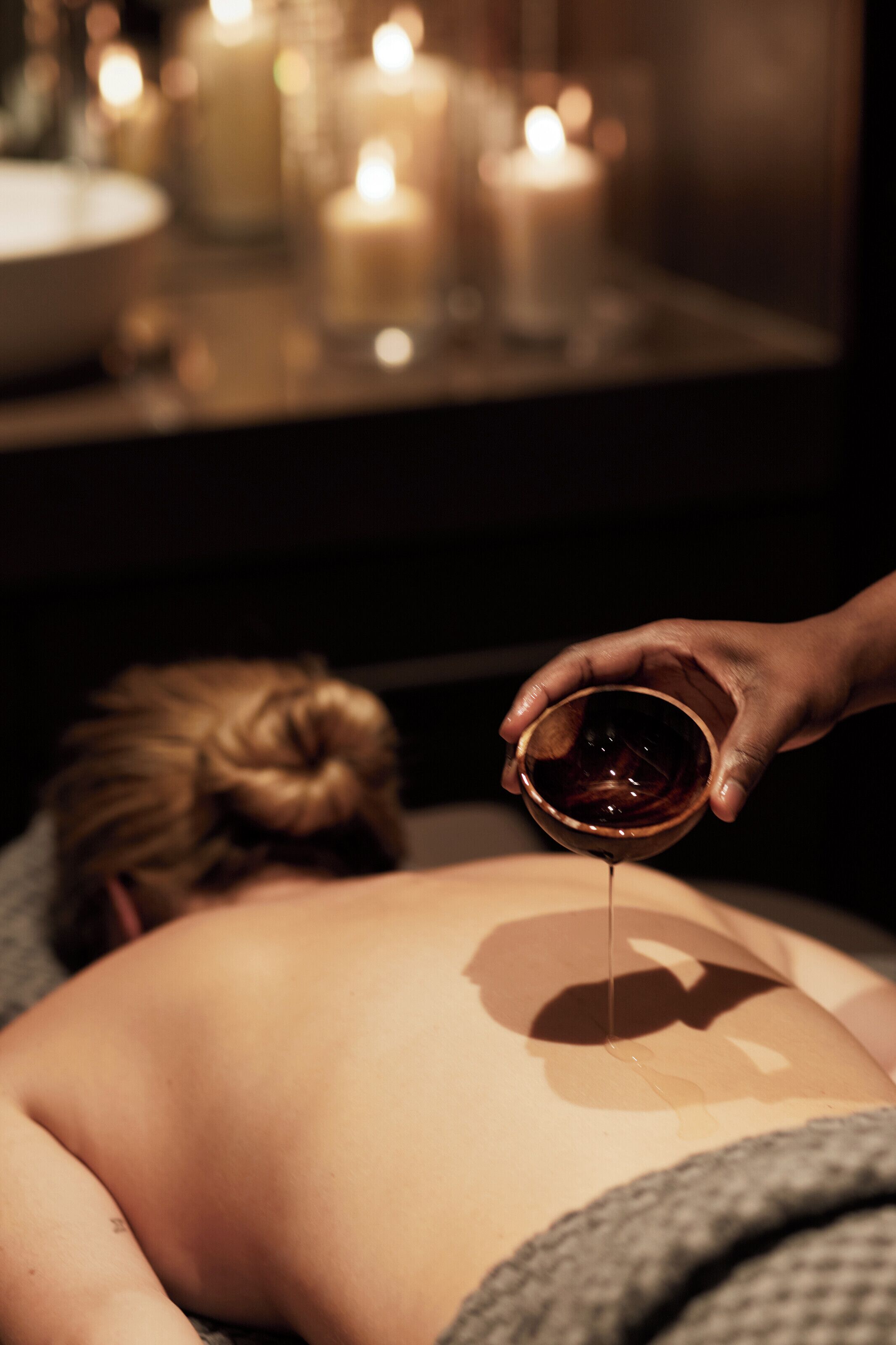 A person receiving a massage with candles in the background.