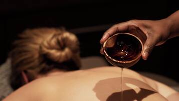 A person receiving a massage with candles in the background.