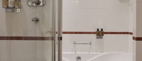 A bathroom with a glass-enclosed shower, a bathtub, and a towel rack.