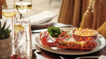 A dining table with a lobster, a bowl of pasta, and various side dishes.