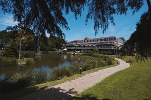A hotel with a large building, a pond, and a walking path. - St Pierre Park Hotel & Golf (St. Peter Port)