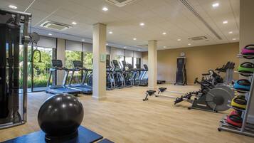 A gym with treadmills, elliptical machines, and exercise balls.