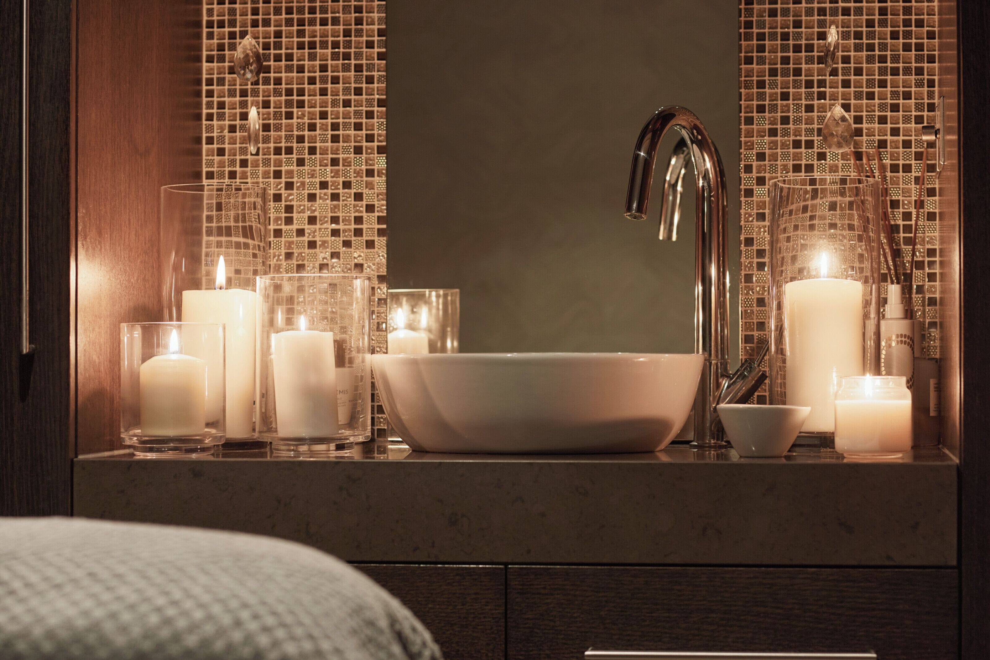 Un baño con un lavamanos grande, varias velas y un espejo con mosaicos.