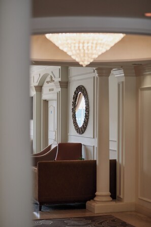 A hotel lobby with a grand chandelier, a large mirror, and a seating area with a brown sofa. - St Pierre Park Hotel & Golf (St. Peter Port)