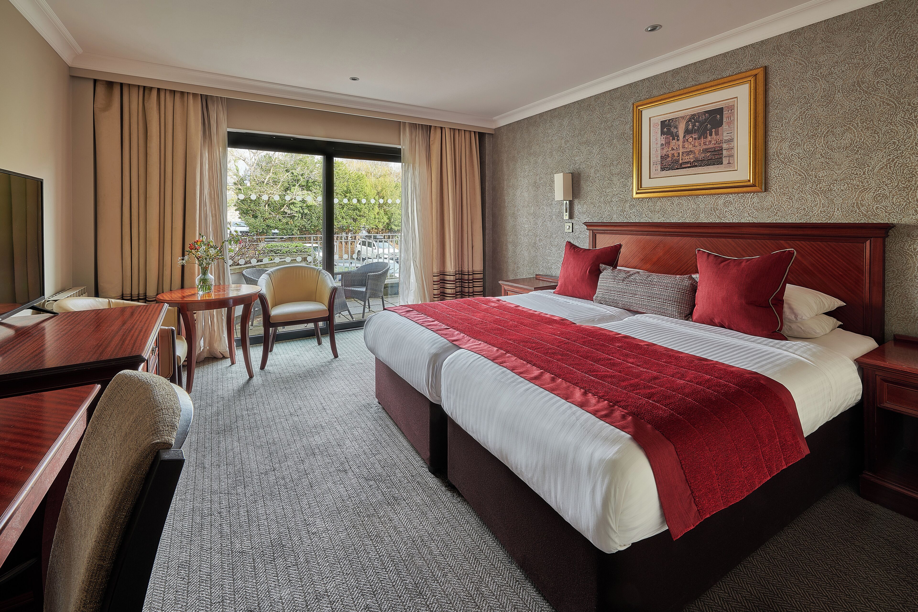 A hotel room with a large bed, a desk, a chair, and a view of the outdoors.