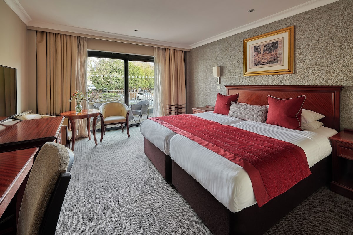Habitación de hotel con una cama grande, un escritorio, una silla y vistas al exterior.
