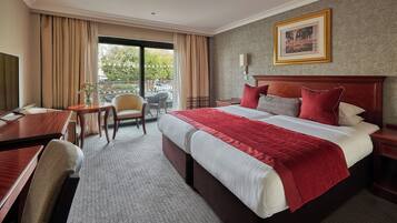 A hotel room with a large bed, a desk, a chair, and a view of the outdoors.