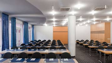 Un salón de conferencias con filas de mesas, sillas y un pilar grande.