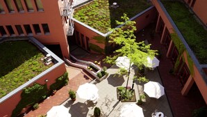 Vue aérienne d’une cour intérieure avec des espaces de détente en plein air, de la verdure et un escalier.