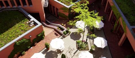 An aerial view of a courtyard with outdoor seating, greenery, and a staircase.