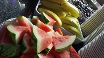Une assiette de fruits contenant de la pastèque, des bananes et des pommes, posée sur un plan de travail de cuisine.