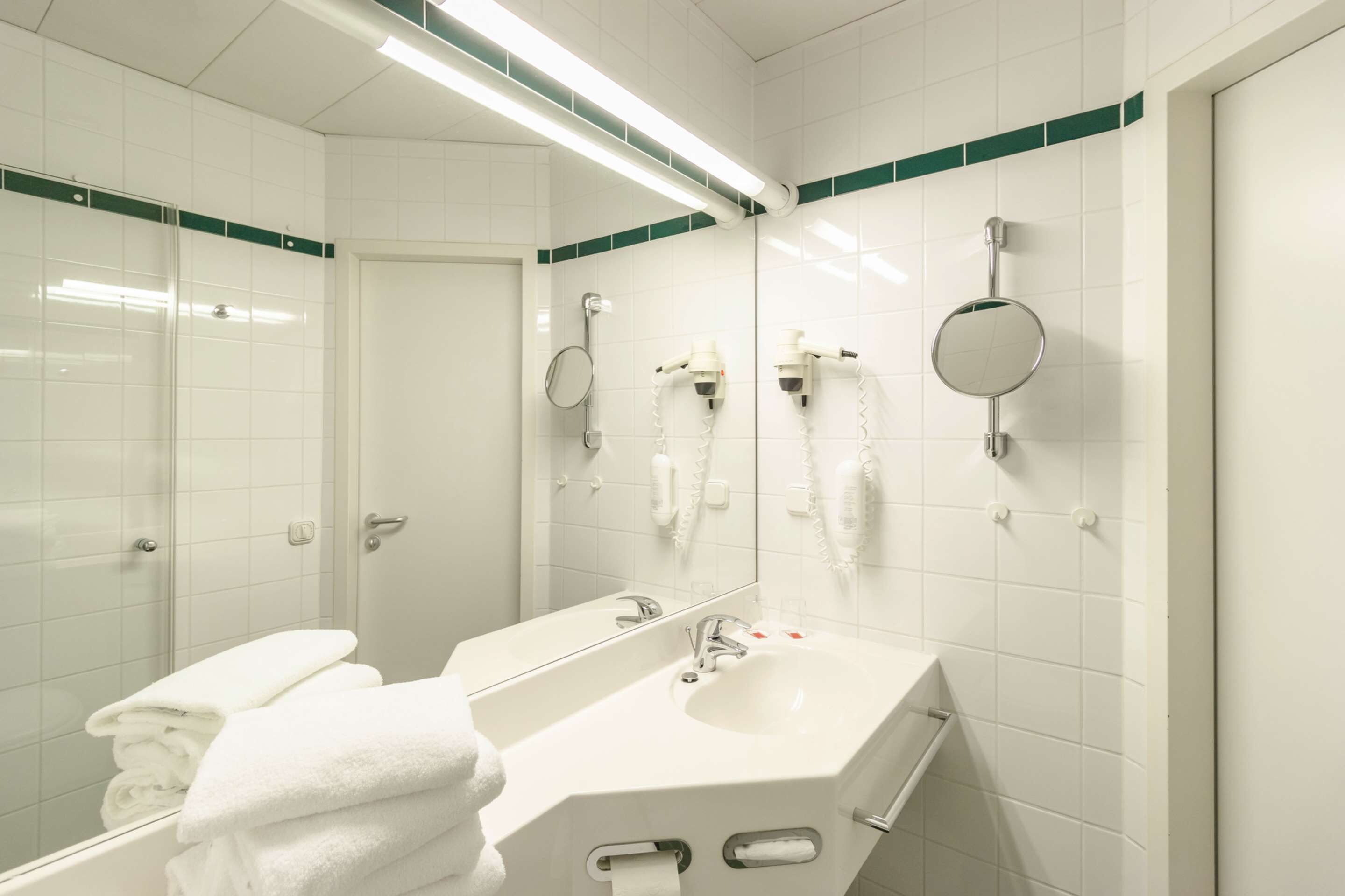 A modern bathroom with a glass shower enclosure, a white sink with a mirror, and a towel rack.
