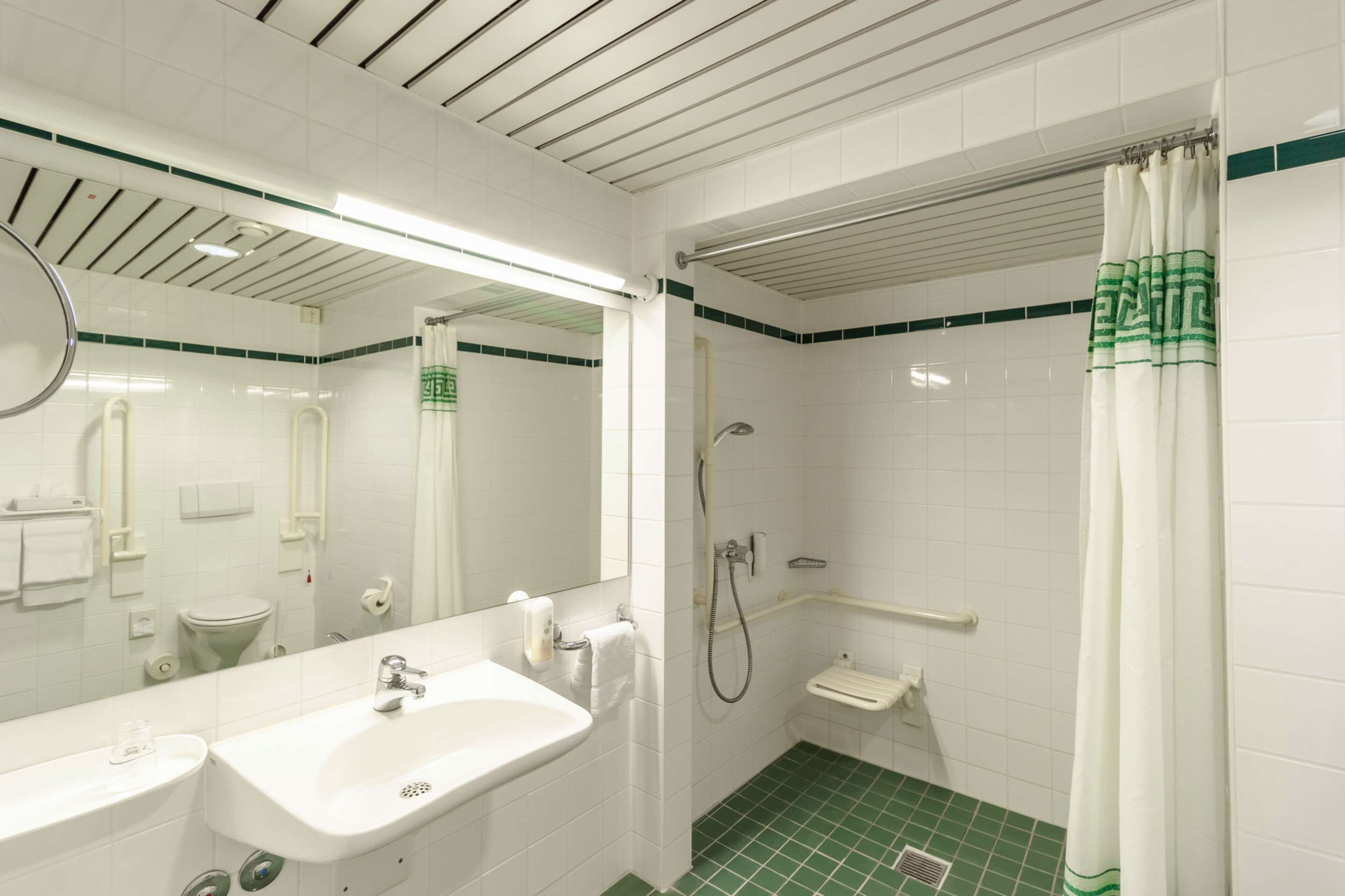 Une salle de bain avec un lavabo blanc, un miroir, des toilettes et une douche.