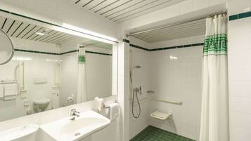 Une salle de bain avec un lavabo blanc, un miroir, des toilettes et une douche.