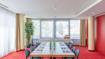 A conference room with a long table, blue chairs, and a potted plant.