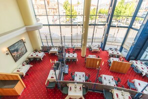 A restaurant with red carpet flooring, white tables, and chairs, large windows with a view of the street. - IntercityHotel Schwerin (Schwerin)
