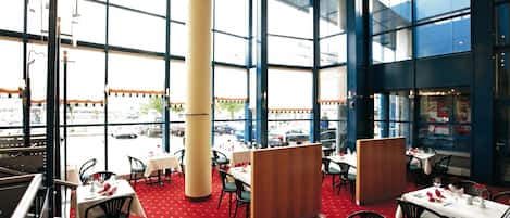 A restaurant with large windows, red carpet, and multiple dining tables.