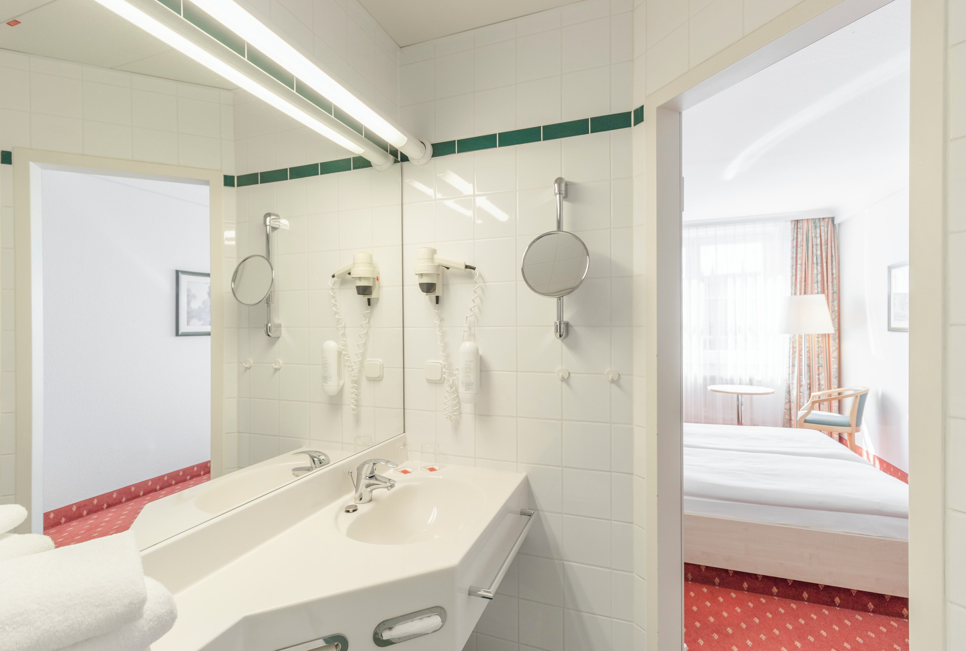 Un baño de hotel con un espejo grande, un lavabo y una ducha.