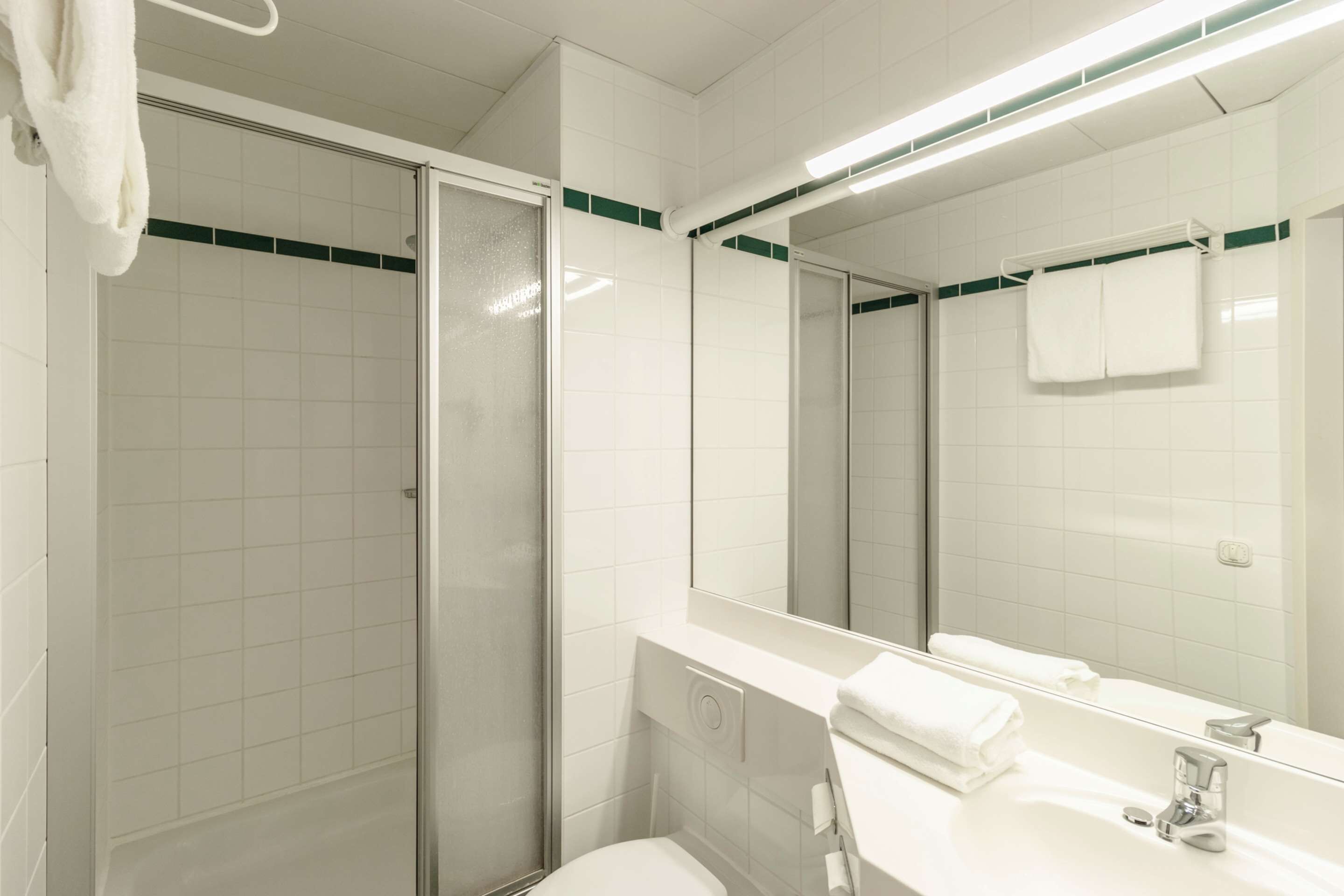 A modern bathroom with a glass shower enclosure, a white sink, and a large mirror.