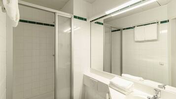 A modern bathroom with a glass shower enclosure, a white sink, and a large mirror.