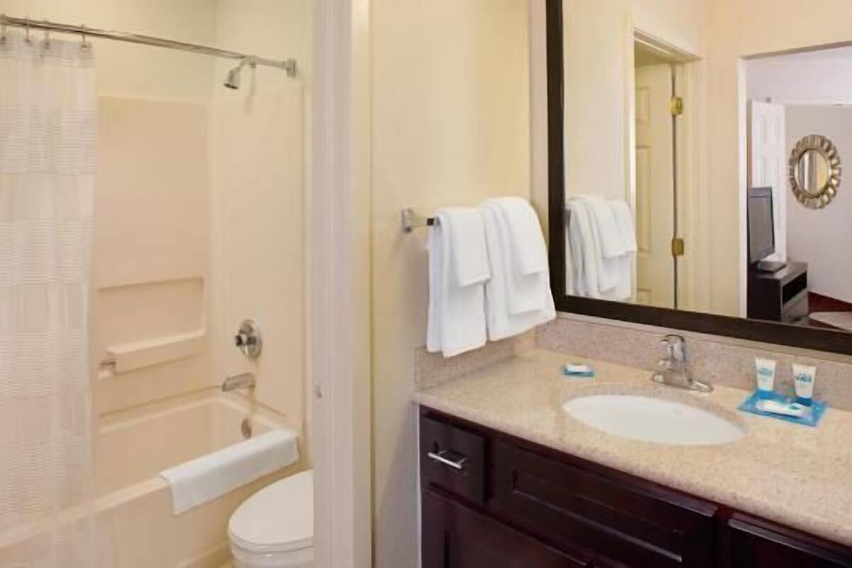 A bathroom with a bathtub, toilet, sink, and a mirror.