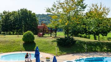 A swimming pool area with a wooden deck, lounge chairs, and umbrellas.