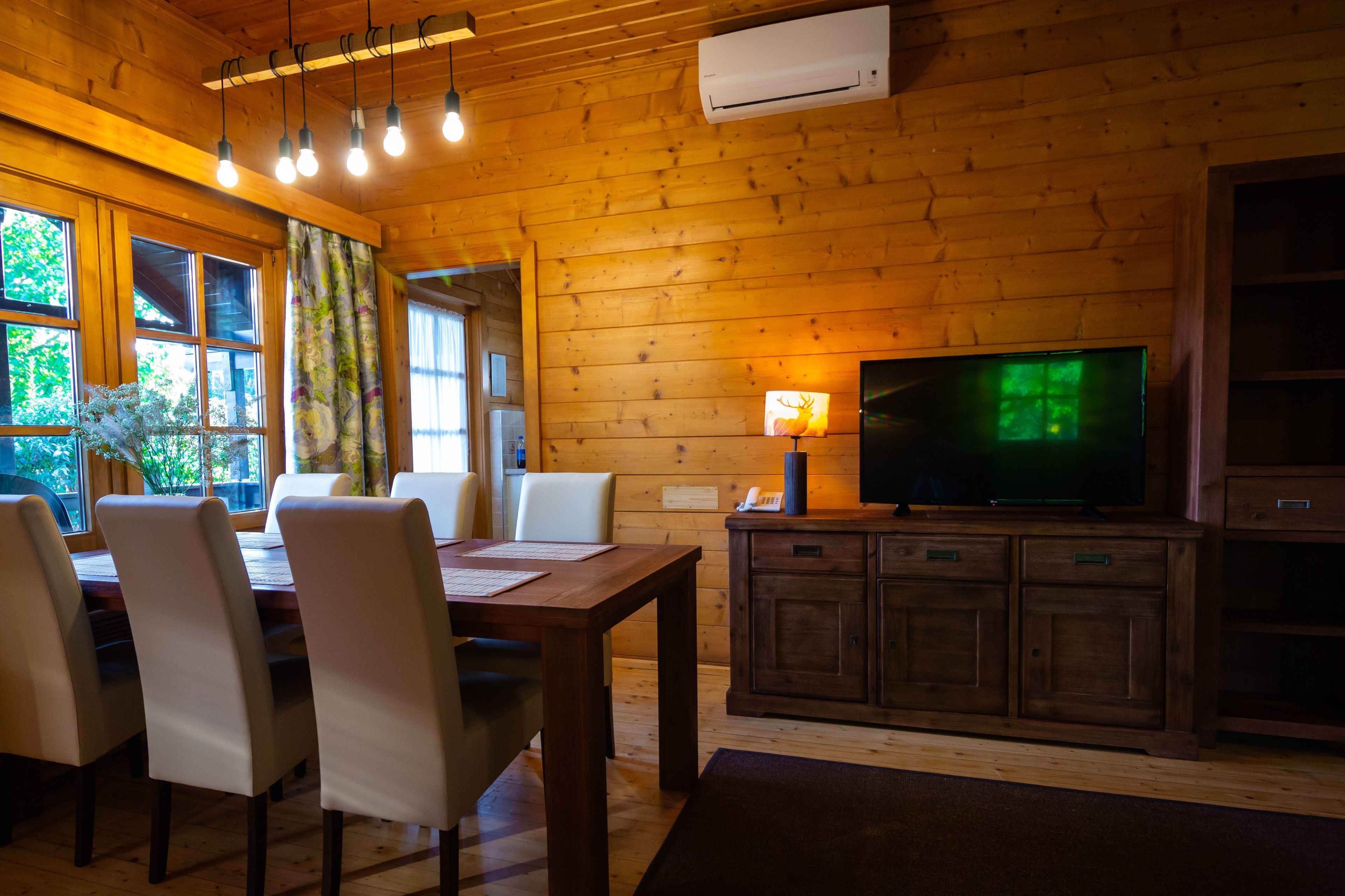Un intérieur en bois comprenant une table à manger, des chaises, un téléviseur et un meuble.