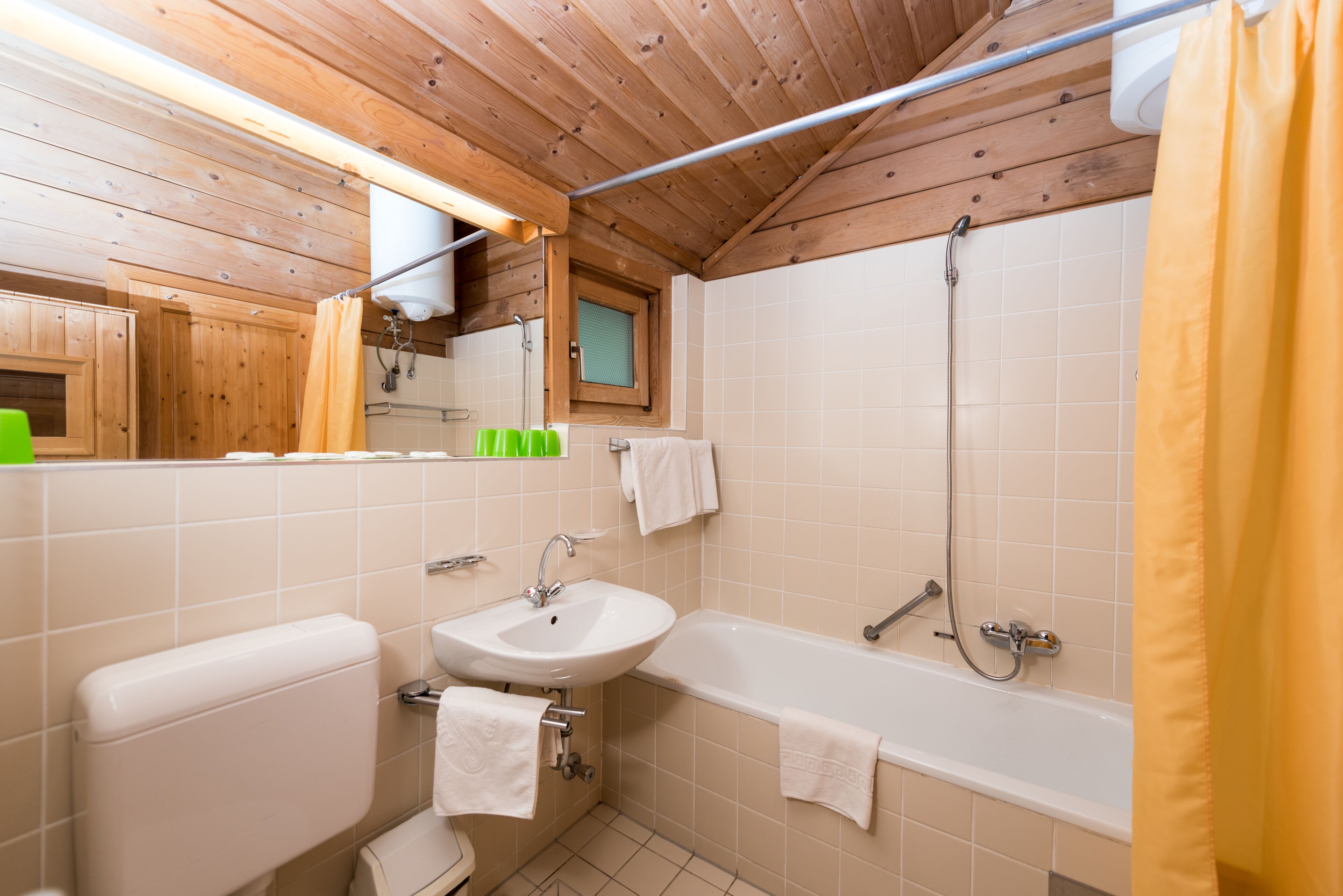A bathroom with a wooden ceiling, a white sink, a bathtub, and a shower.