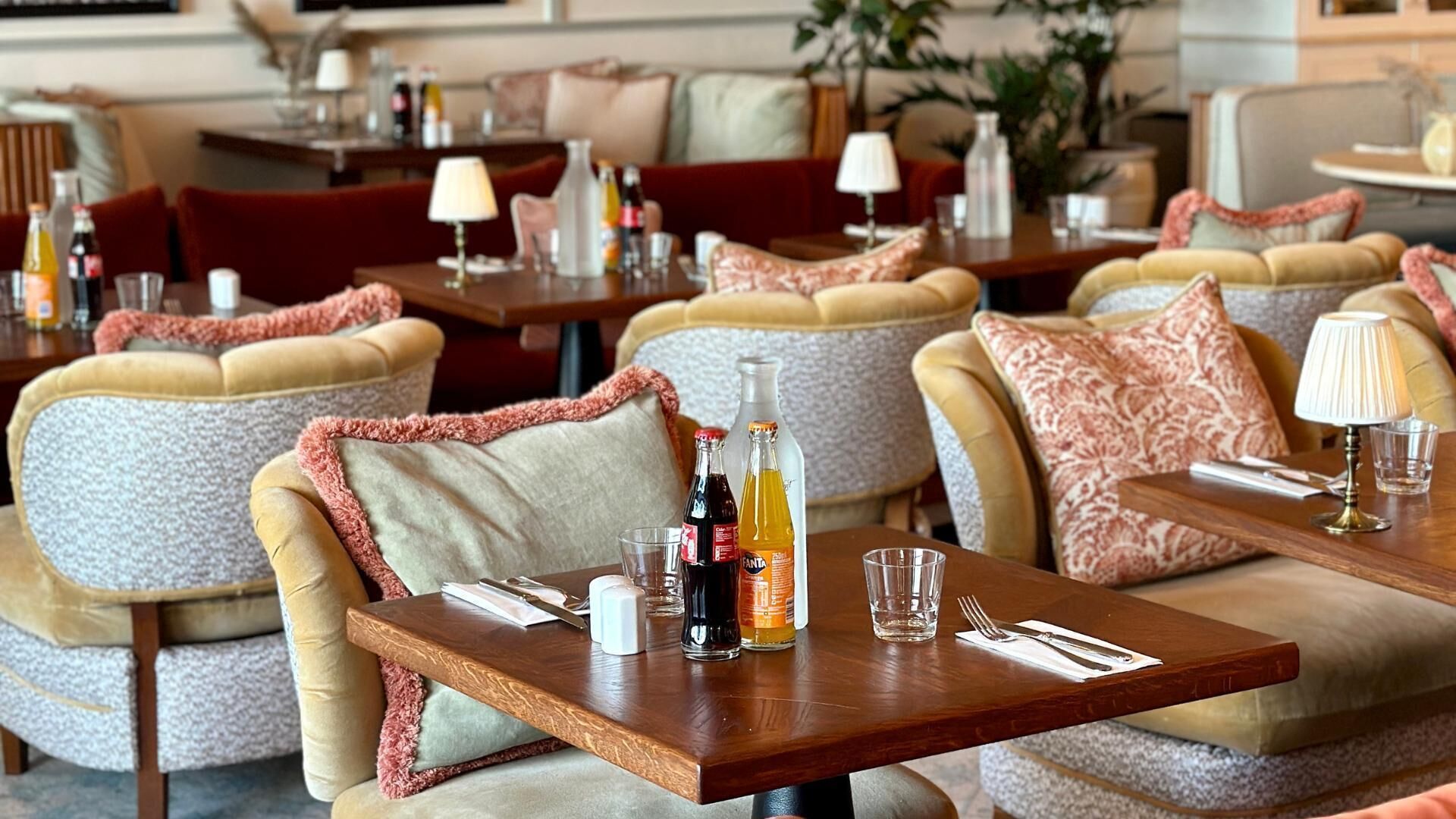 Un restaurant avec des banquettes rembourrées et des tables en bois, chaque table étant dressée avec un verre, une serviette et des couverts.