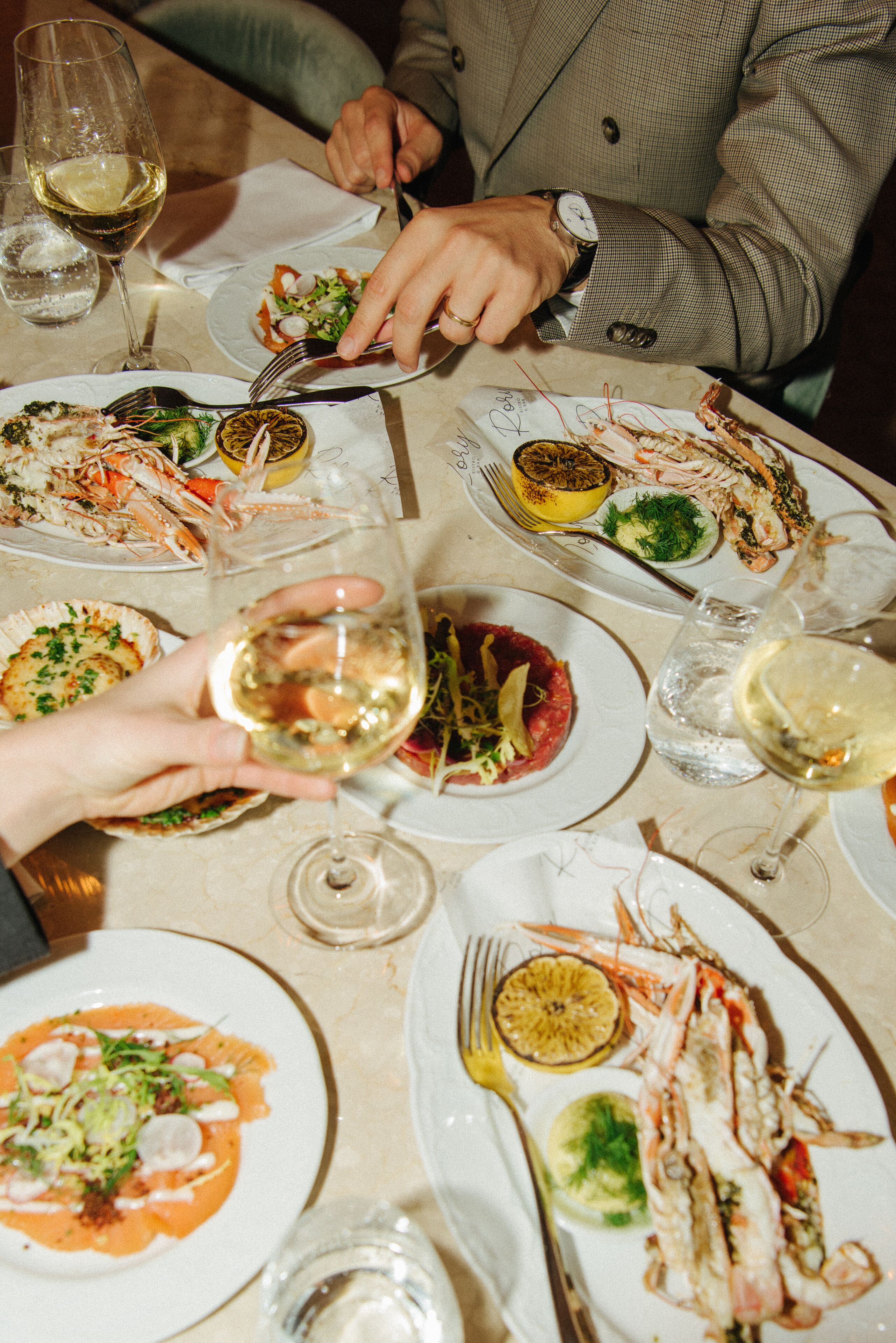 A dining table with various dishes and wine glasses.