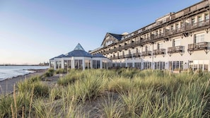 A coastal hotel with a glass-roofed pavilion and a multi-story building with balconies.