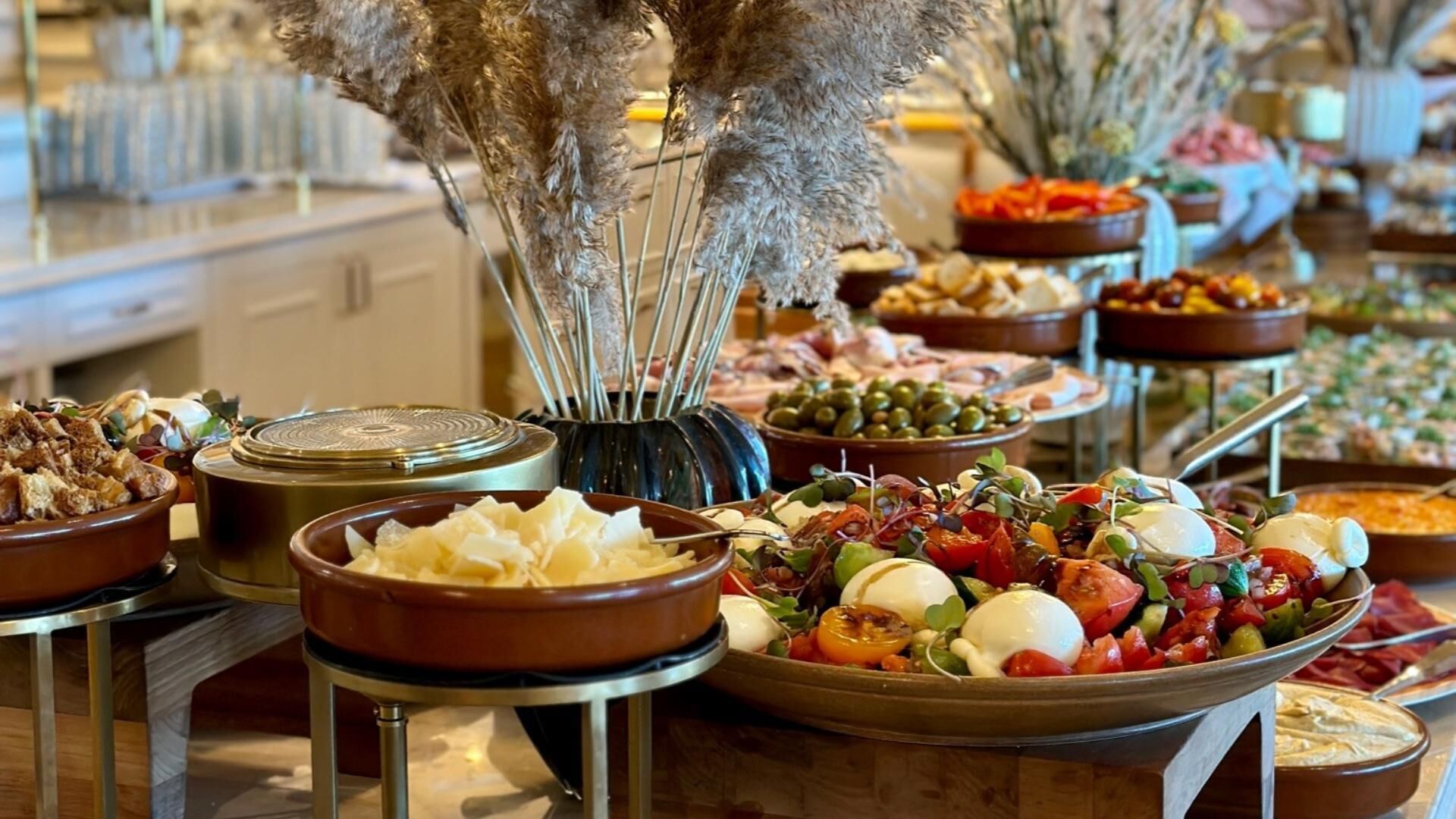 A buffet with various dishes including cheeses, meats, and vegetables.