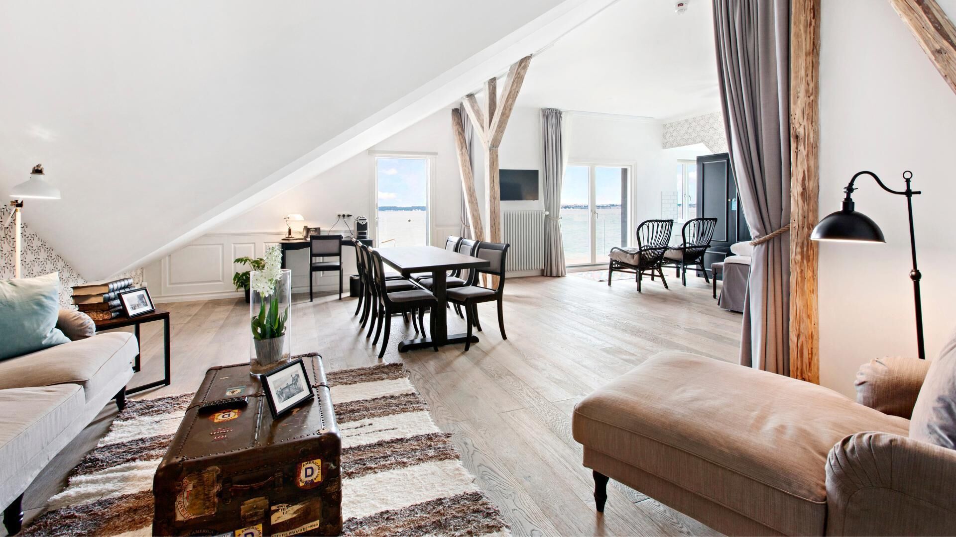 Un amplio apartamento tipo loft con techos altos, una zona de comedor y un área de estar con vista al agua.