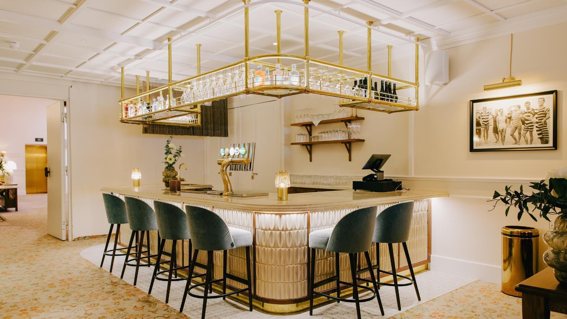 Eine Bar mit einer gebogenen Theke, mehreren Barhocker und einer dekorativen Deckenkonstruktion.