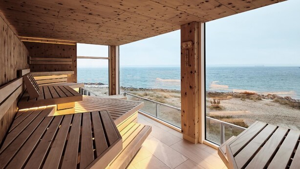 Une terrasse en bois avec des bancs donnant sur une plage.
