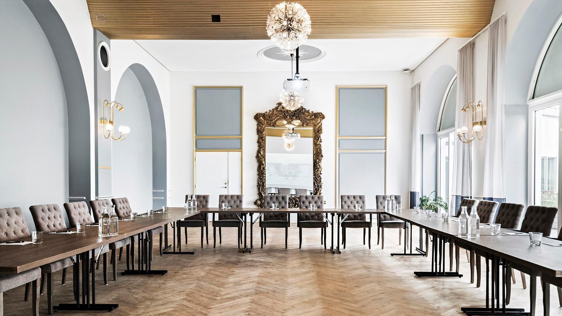A conference room with a long table, chairs, and a large ornate mirror.