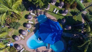 Eine Vogelperspektive eines Resorts mit Swimmingpool, Liegestühlen und Sonnenschirmen.