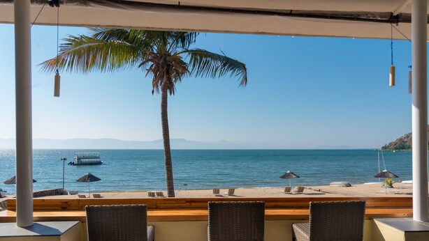 Eine Strandbar mit Korbstühlen und Blick auf den Ozean.