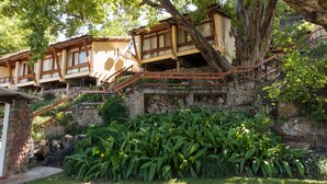 Ein Gebäude im traditionellen Stil mit mehreren hölzernen Balkonen, Steinmauern und üppigem Grün.