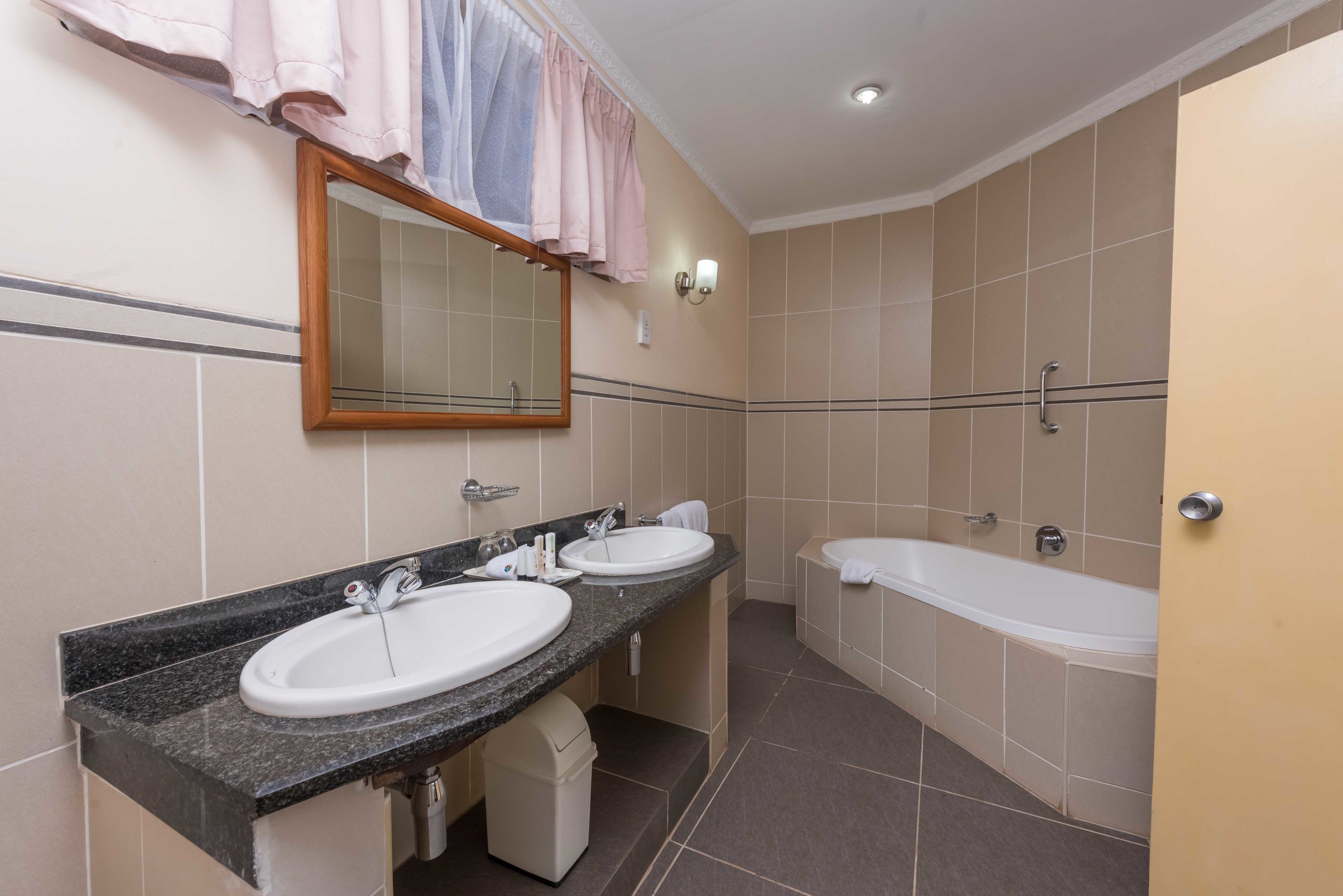 A bathroom with two sinks, a bathtub, and a mirror.