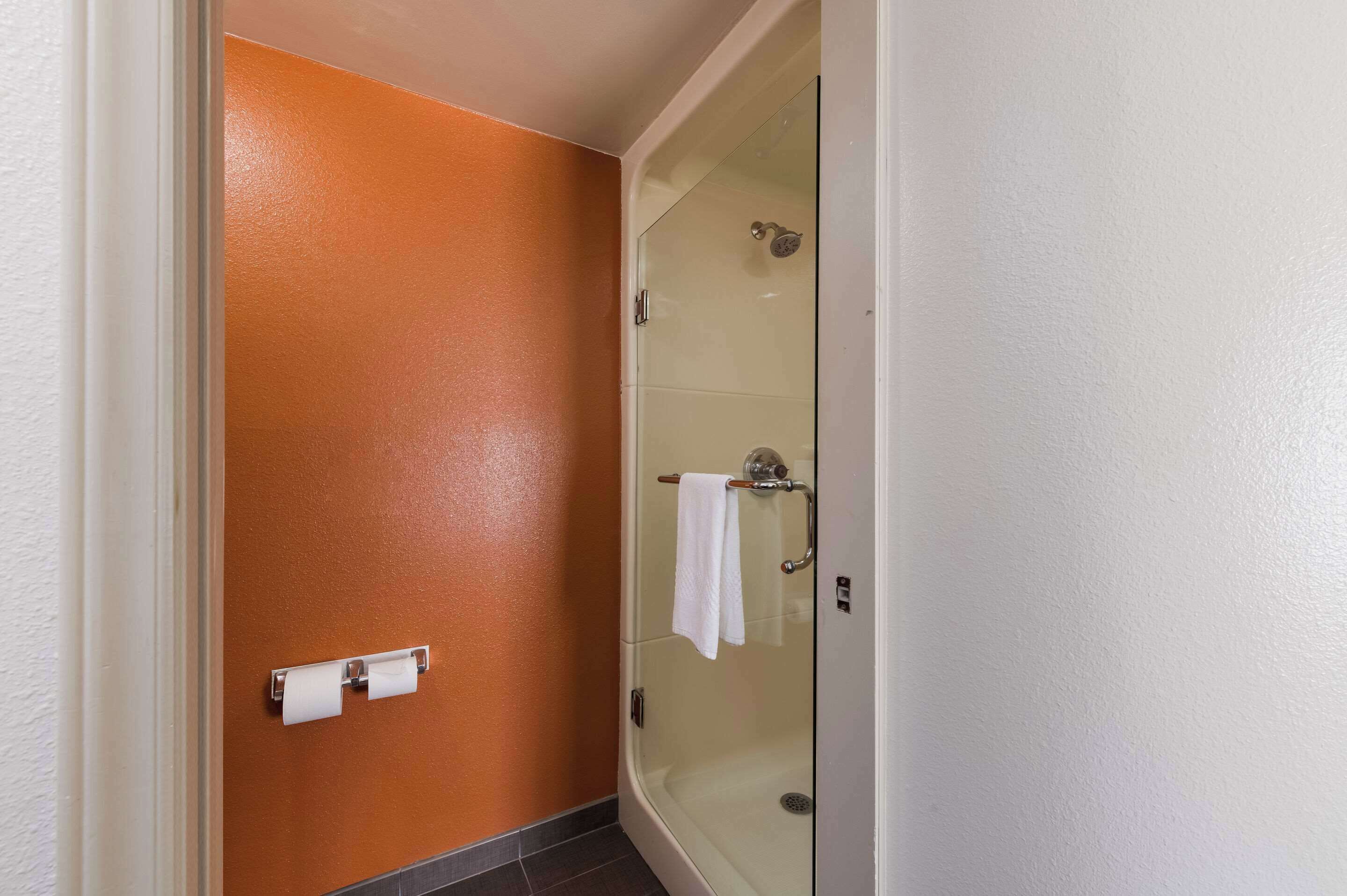 A bathroom with a glass shower enclosure, a towel rack, and a toilet paper holder.