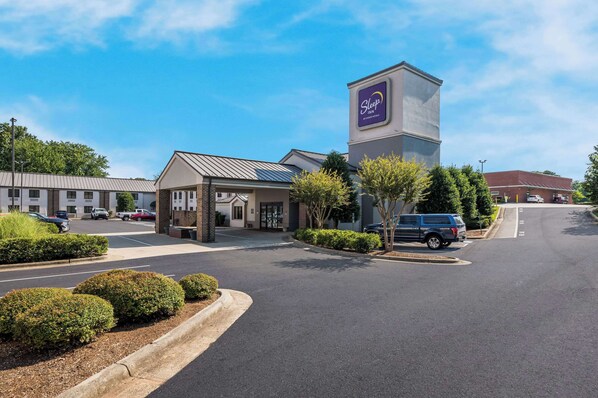 A Sleep Inn with a modern design, featuring a prominent tower with the Sleep Inn logo, a parking lot, and well-maintained landscaping.