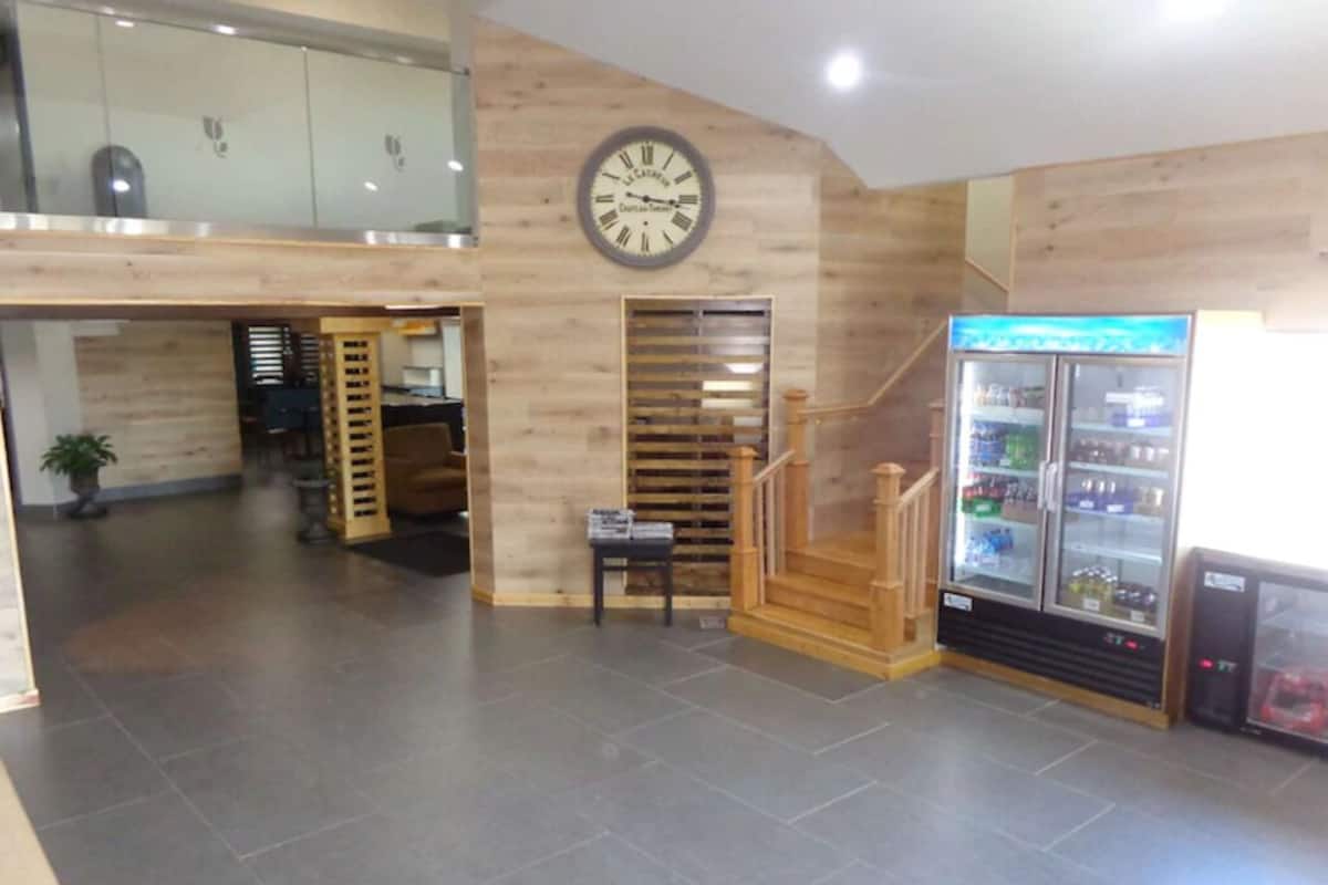 Un vestíbulo con una escalera de madera, un reloj y una máquina expendedora.