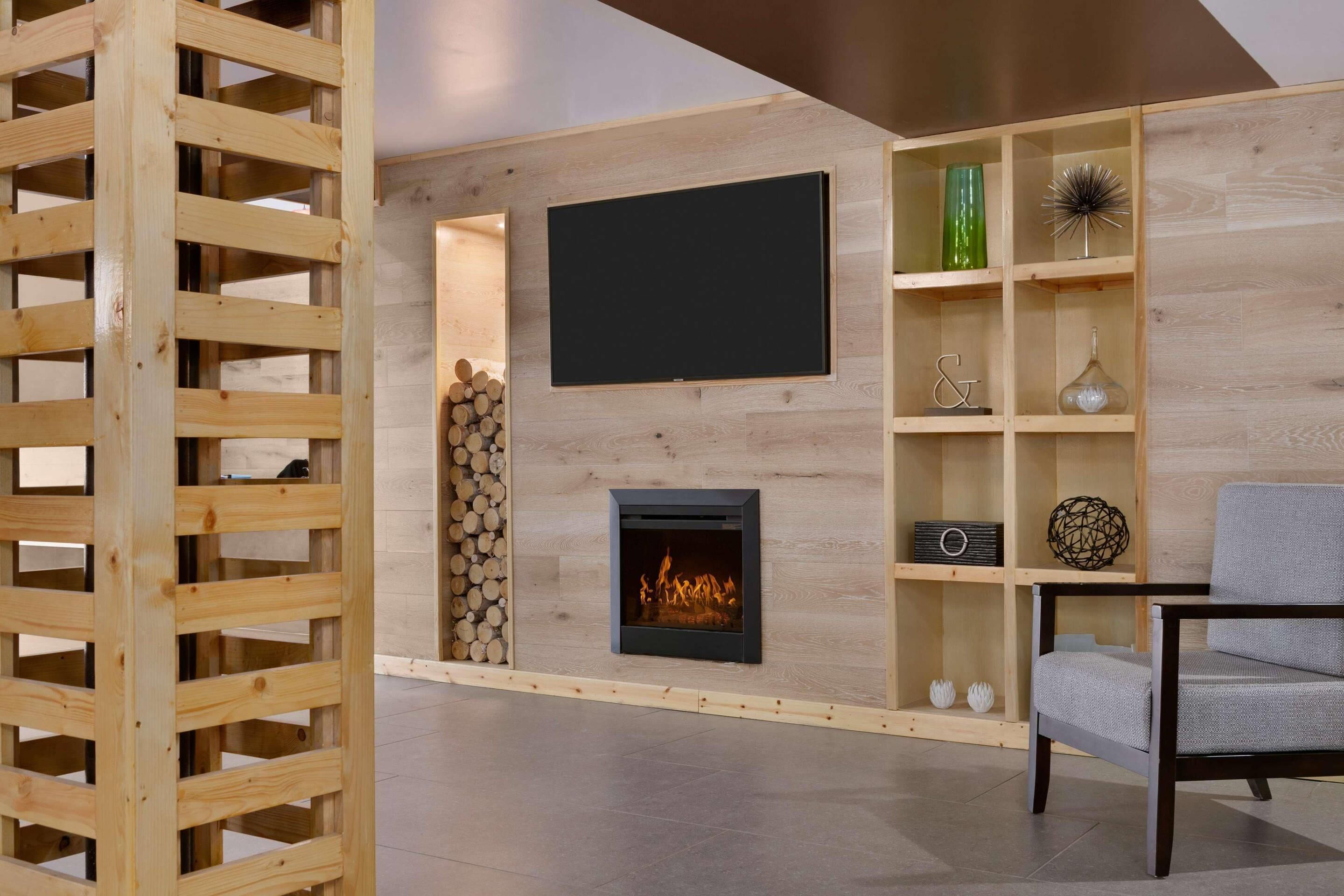 A modern living room with a fireplace, a television mounted on the wall, and a wooden bookshelf.