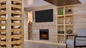 A modern living room with a fireplace, a television mounted on the wall, and a wooden bookshelf.
