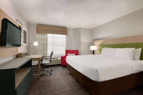 A hotel room with a bed, desk, chair, TV, and a window with curtains. - Country Inn & Suites by Radisson, Roanoke Rapids, NC (Roanoke Rapids)