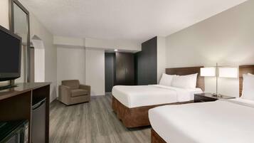 A hotel room with a bed, a chair, a desk with a television, and a lamp.
