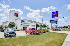 A motel with a prominent '6' sign, a flag, and a sign for an outdoor pool. - Motel 6 Katy, TX - Houston (Katy)